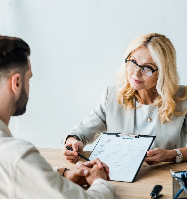 selective-focus-of-recruiter-in-glasses-holding-pen-near-clipboard-and-looking-at-bearded-man.jpg